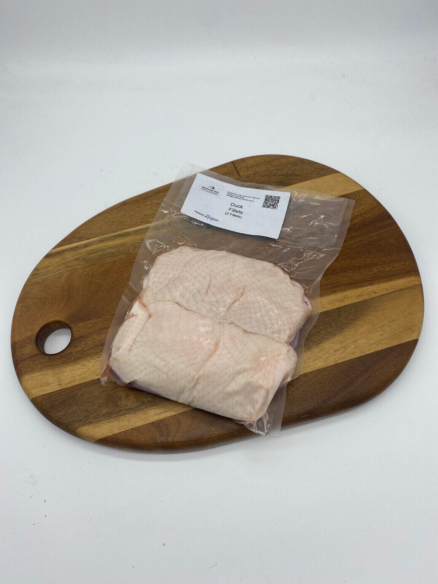 Photo of two (2) duck fillets cryovac on a wooden board