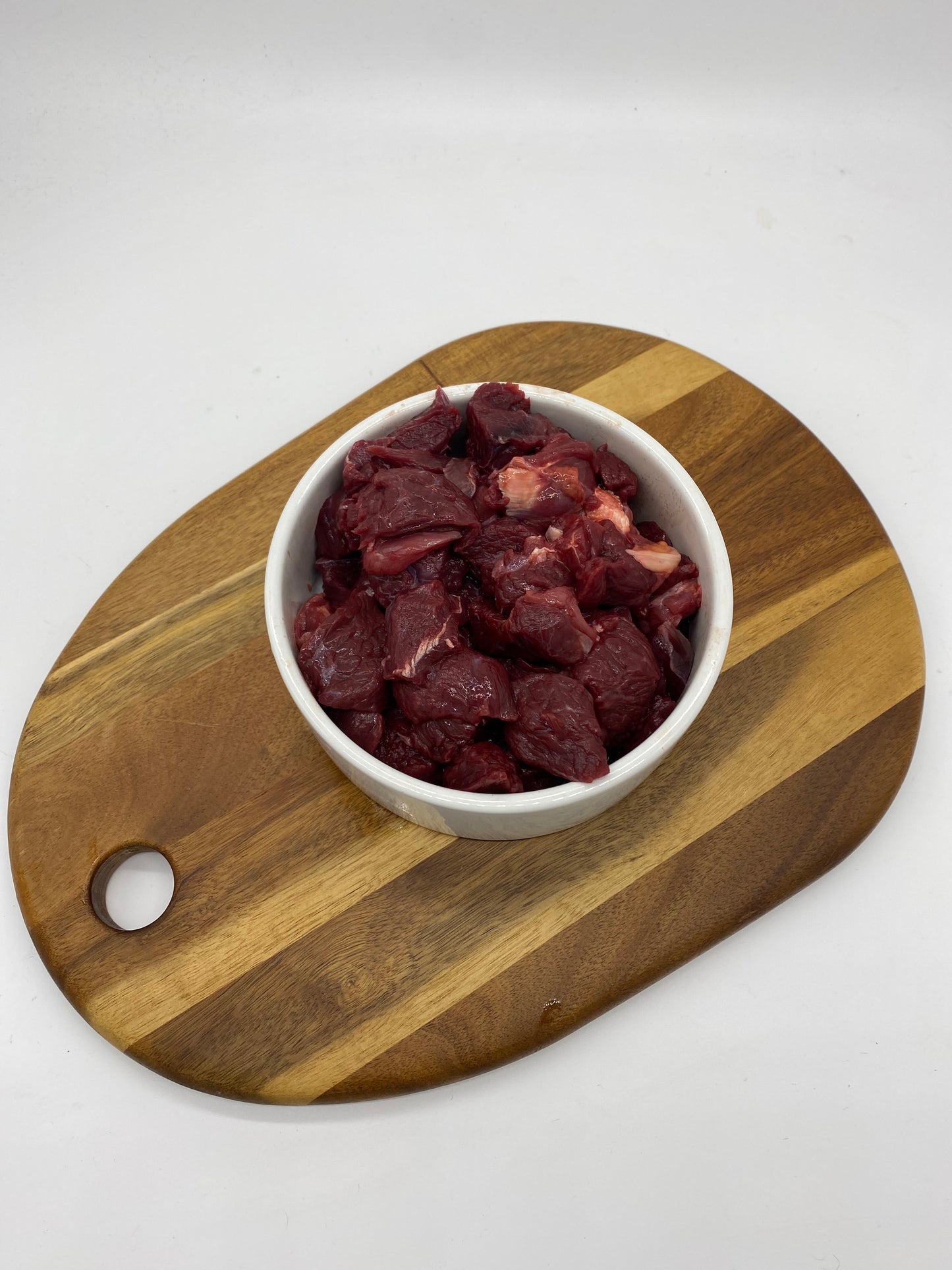 Diced kangaroo meat in a white dog bowl overhead view