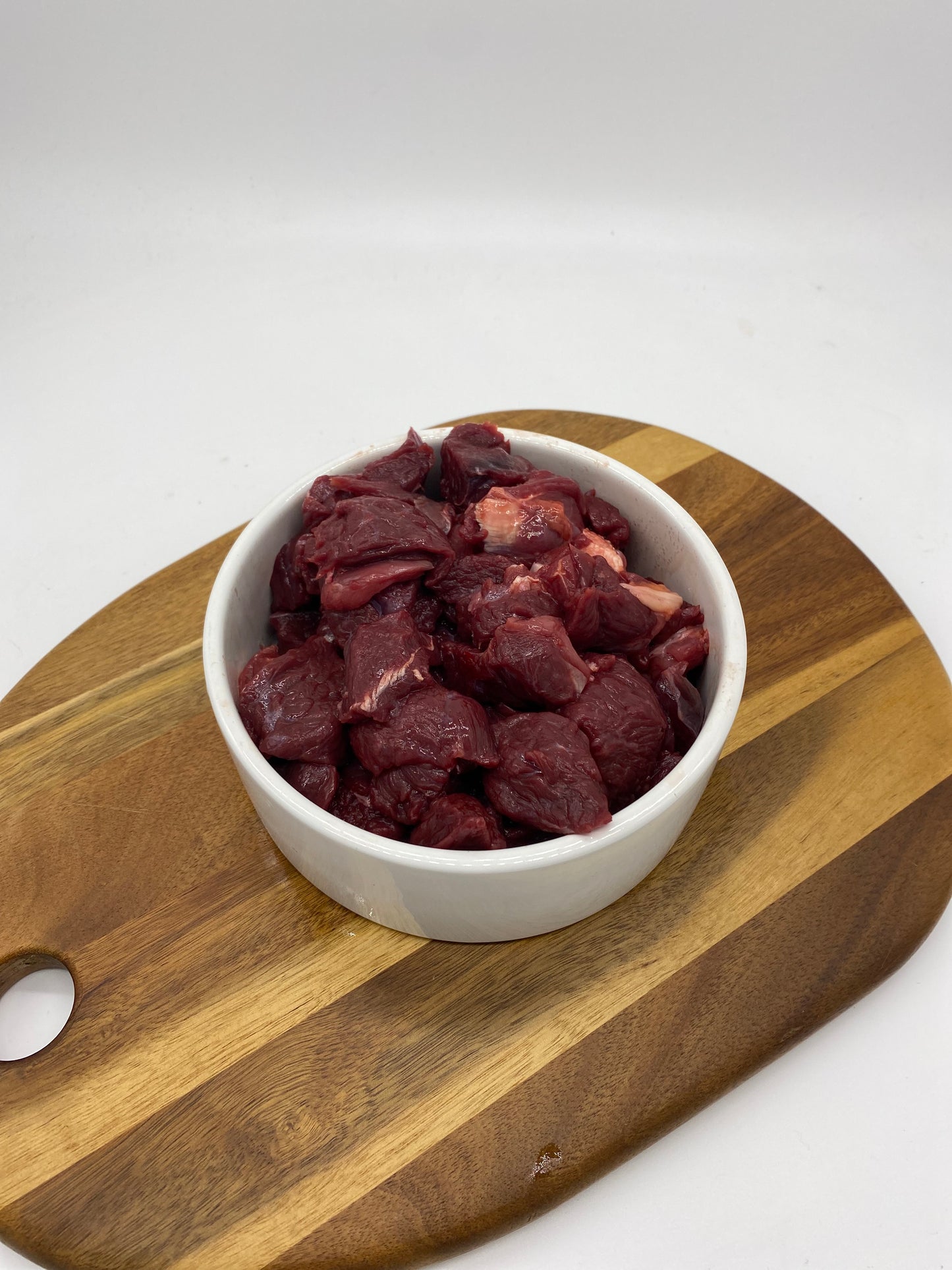 Diced kangaroo meat in a white dog bowl overhead view