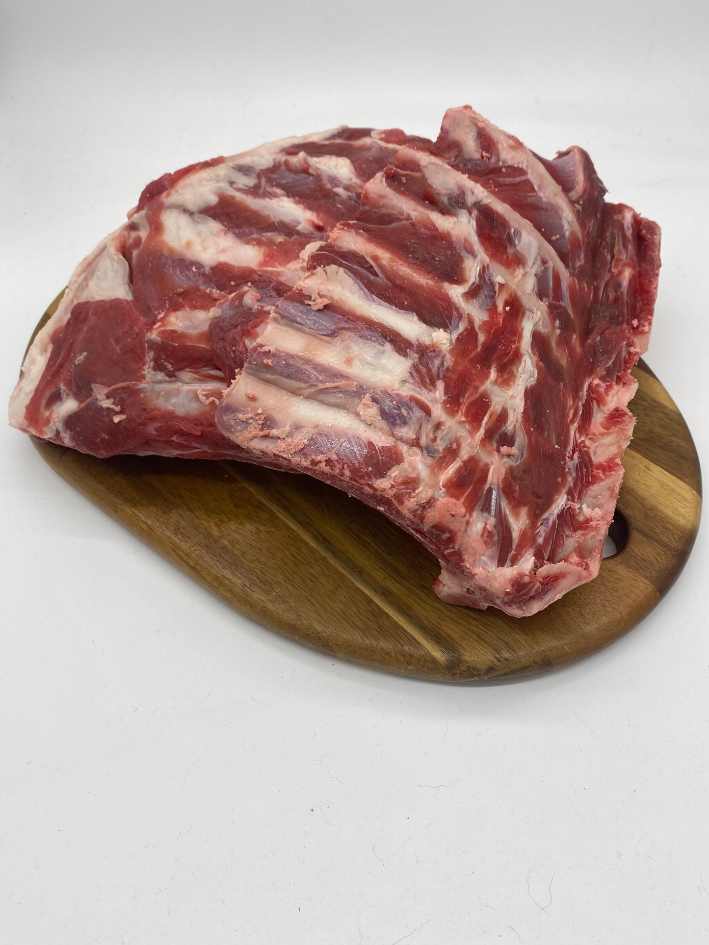 Photo - raw goat ribs on a wooden board