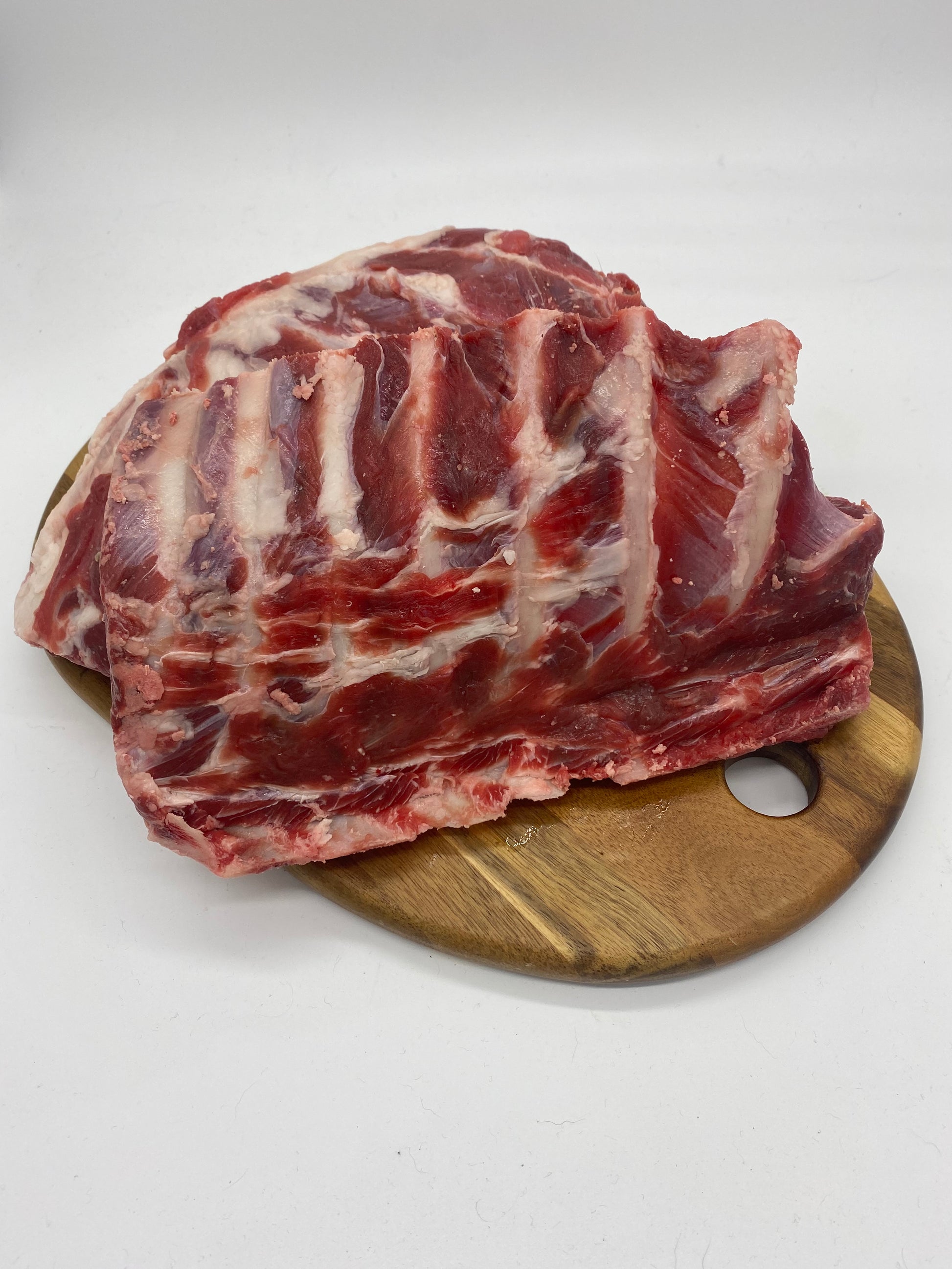 Photo - Raw goat ribs on a wooden board