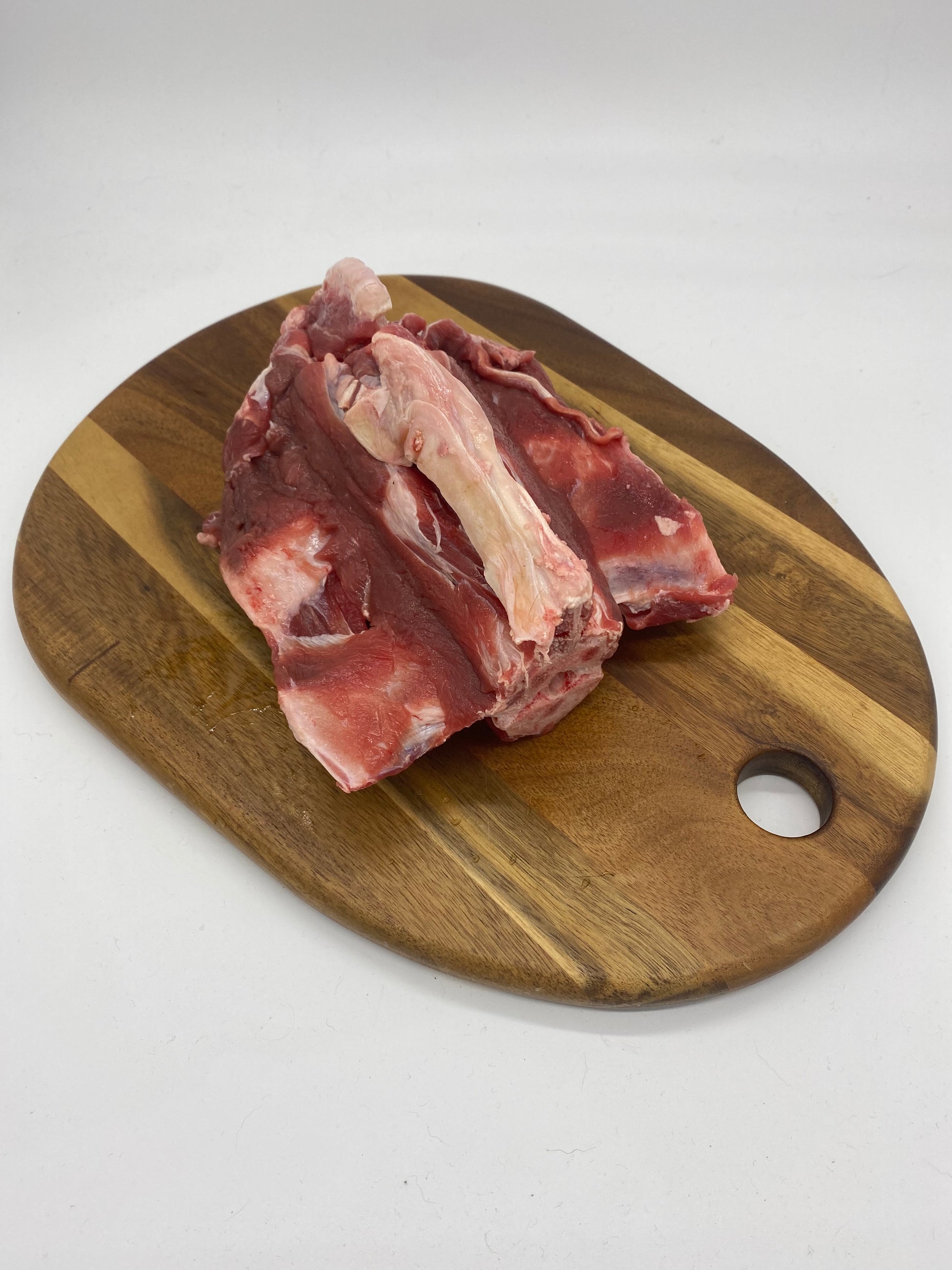 Photo - raw goat spine section on a wooden board