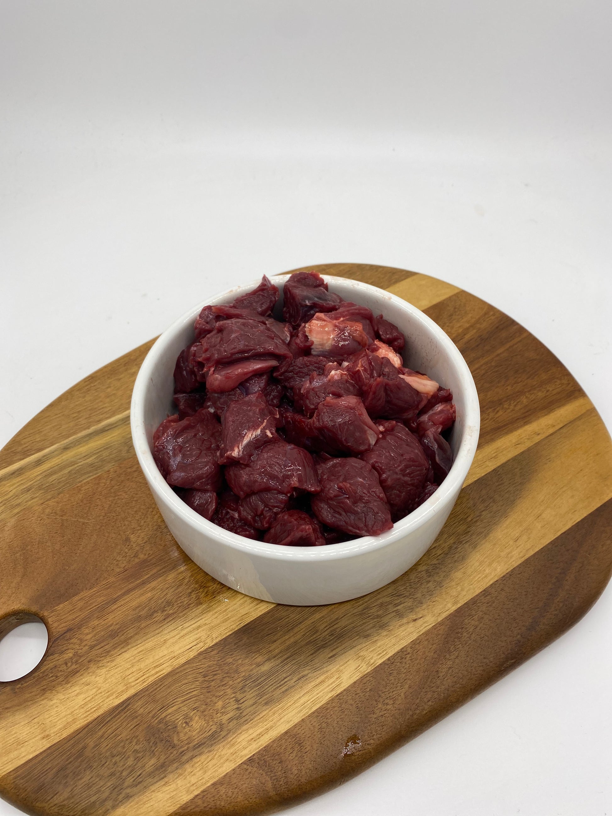 Diced kangaroo meat in a white dog bowl overhead view