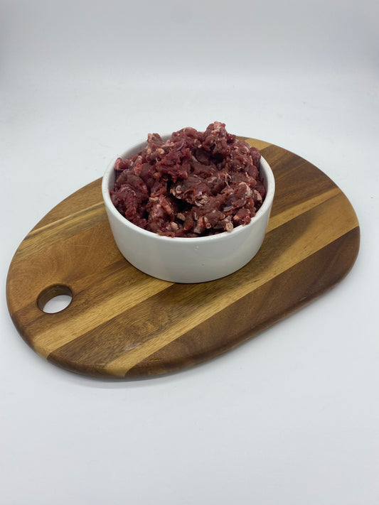 Minced Venison in a white bowl on a wooden board